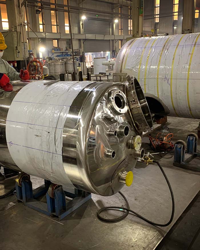 A worker polishing a new custom made bioreactor for yeast propagation service designed and engineered by The Engine Room